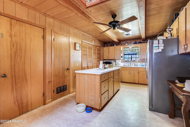 kitchen featuring wooden walls, ceiling fan, beamed ceiling, stainless steel refrigerator, and wooden ceiling