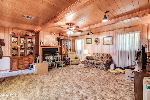 living room featuring carpet floors, a healthy amount of sunlight, ceiling fan, and beamed ceiling