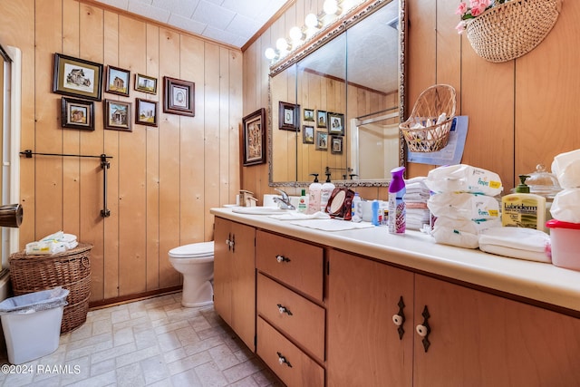 bathroom featuring oversized vanity, toilet, ornamental molding, and wood walls