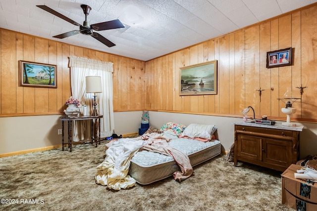 bedroom featuring wood walls, light colored carpet, and ceiling fan