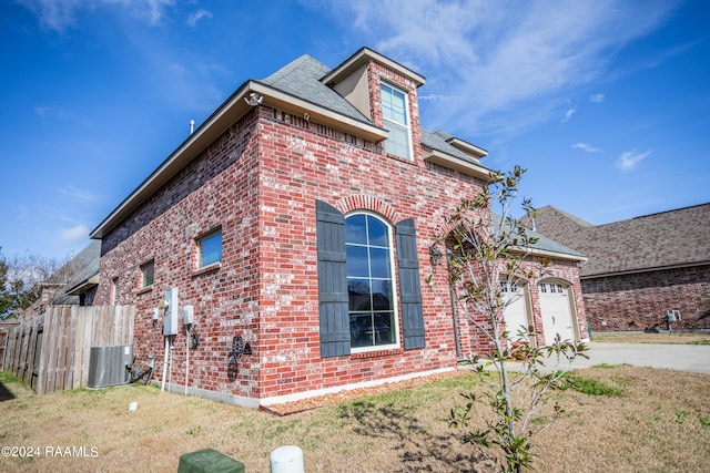 view of side of property featuring central AC unit, a lawn, and a garage