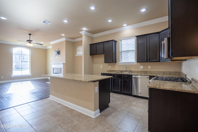 kitchen featuring a center island, light stone counters, ceiling fan, stainless steel appliances, and light tile floors