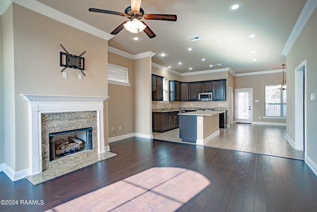 unfurnished living room featuring ceiling fan, crown molding, a fireplace, and light tile floors