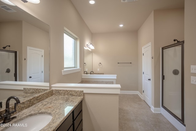 bathroom featuring tile floors, vanity, and a shower with shower door