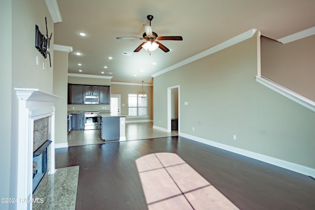 unfurnished living room with ornamental molding, dark hardwood / wood-style floors, ceiling fan, and a fireplace