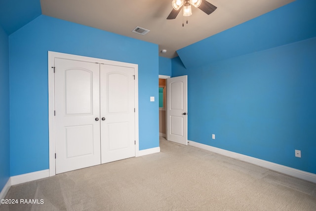 unfurnished bedroom featuring a closet, ceiling fan, vaulted ceiling, and light colored carpet