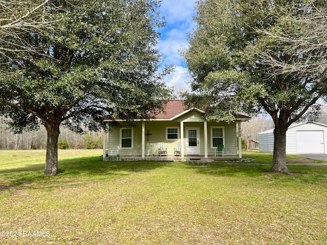 view of front of home featuring an outdoor structure, covered porch, a front yard, and a garage