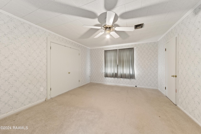 empty room with ceiling fan, light colored carpet, and ornamental molding