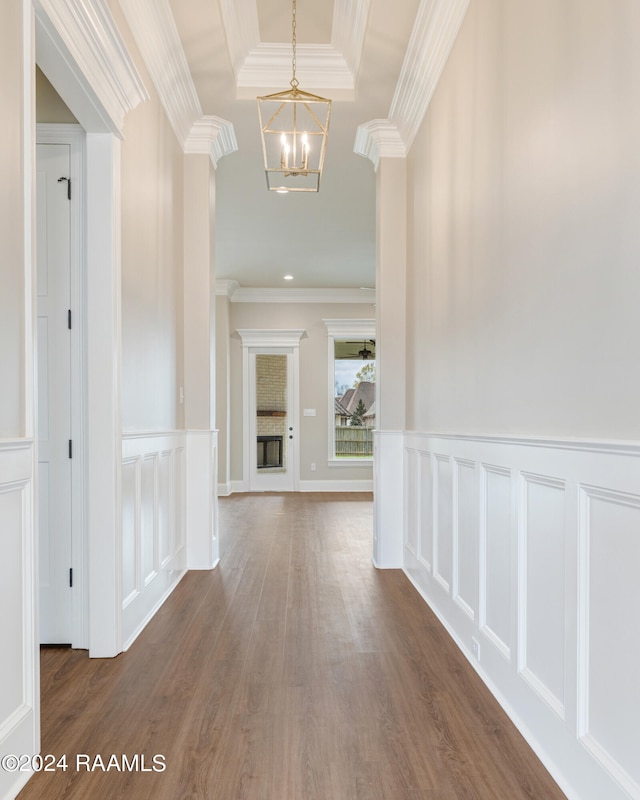 hallway featuring an inviting chandelier, a tray ceiling, dark wood-type flooring, and ornamental molding