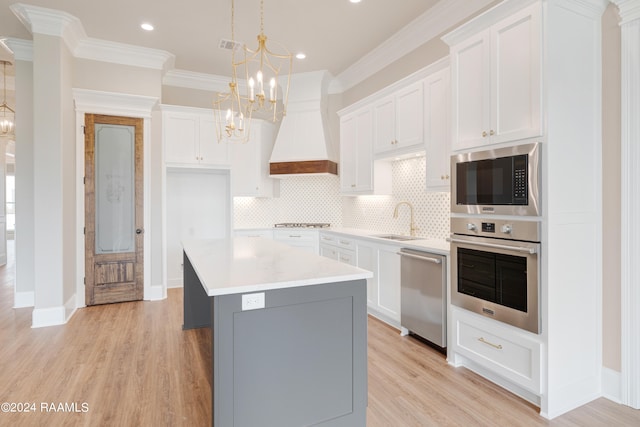 kitchen featuring an inviting chandelier, tasteful backsplash, stainless steel appliances, premium range hood, and white cabinets