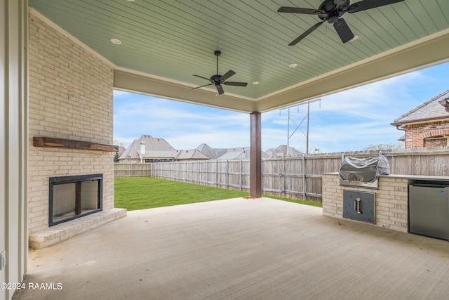 view of patio / terrace featuring an outdoor brick fireplace, exterior kitchen, grilling area, and ceiling fan