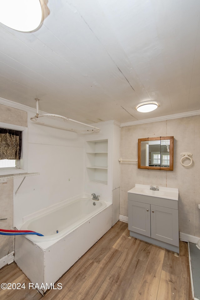 bathroom featuring built in features, ornamental molding, wood-type flooring, and vanity with extensive cabinet space