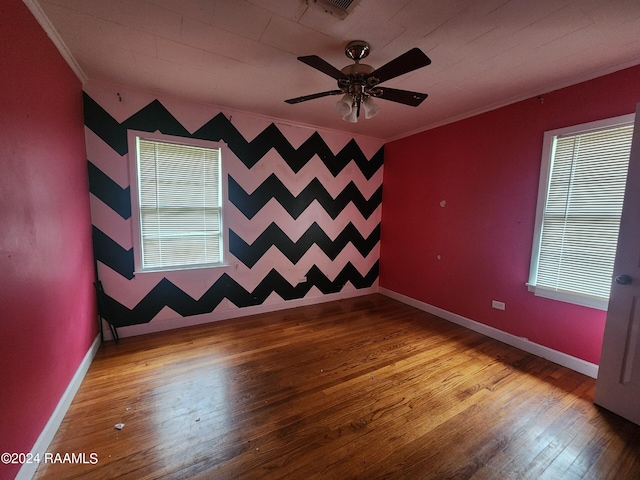 spare room with wood-type flooring, crown molding, and plenty of natural light