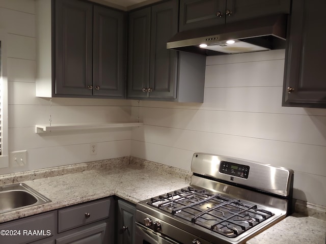 kitchen with tasteful backsplash, light stone counters, and stainless steel gas range