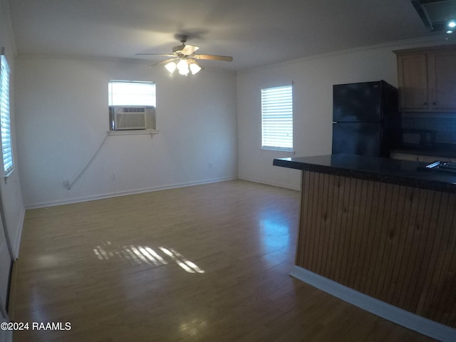 kitchen featuring hardwood / wood-style floors, cooling unit, black fridge, crown molding, and ceiling fan