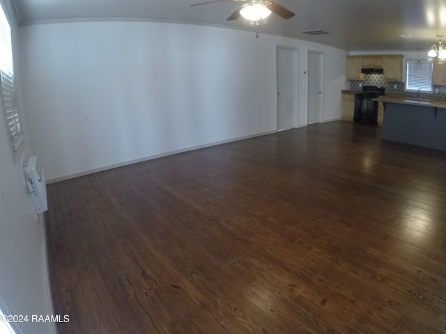 unfurnished living room with ceiling fan with notable chandelier, dark hardwood / wood-style flooring, and ornamental molding