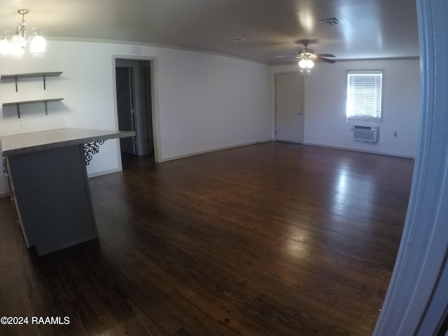 unfurnished living room with a wall unit AC, dark hardwood / wood-style flooring, and ceiling fan with notable chandelier