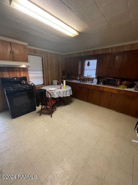 interior space with light tile flooring, black range oven, custom range hood, and crown molding