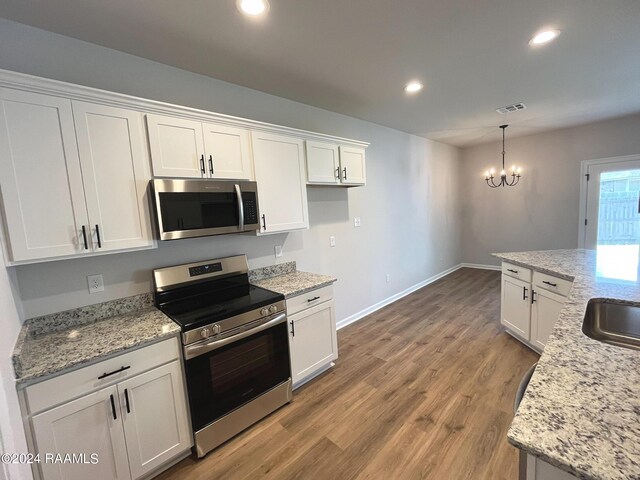 kitchen featuring appliances with stainless steel finishes, an inviting chandelier, light hardwood / wood-style flooring, and white cabinets