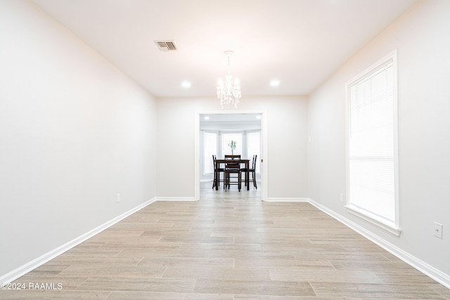 empty room with light hardwood / wood-style flooring and a notable chandelier