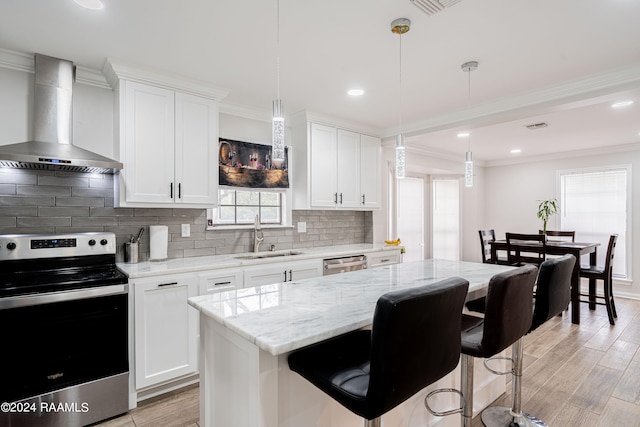 kitchen featuring appliances with stainless steel finishes, pendant lighting, tasteful backsplash, wall chimney range hood, and sink