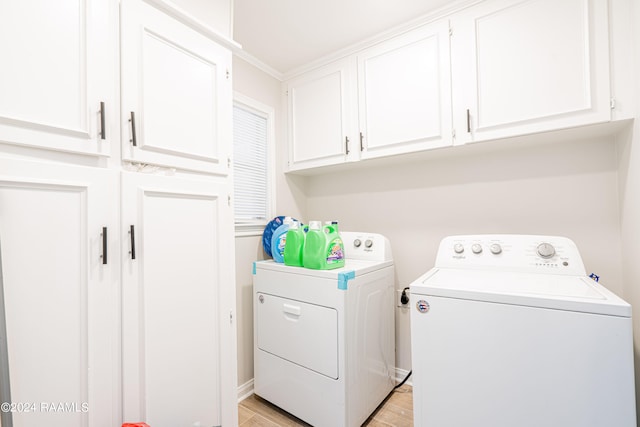 clothes washing area with crown molding, light hardwood / wood-style floors, cabinets, and separate washer and dryer