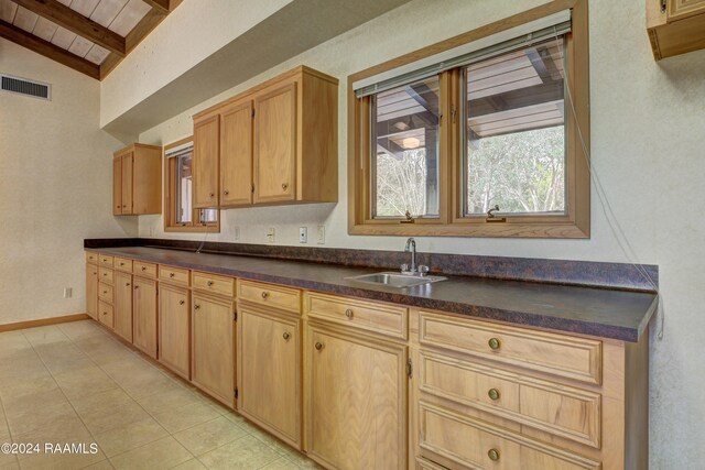 kitchen with lofted ceiling, light tile floors, and sink