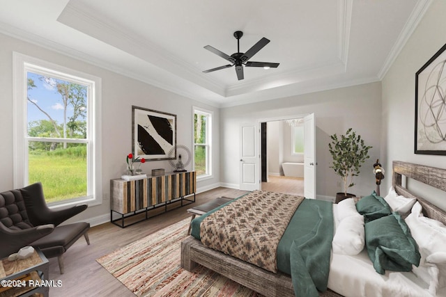 bedroom with light hardwood / wood-style floors, a tray ceiling, ornamental molding, and ceiling fan