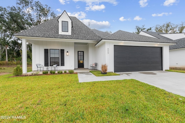 view of front of home featuring a garage, a front yard, and covered porch