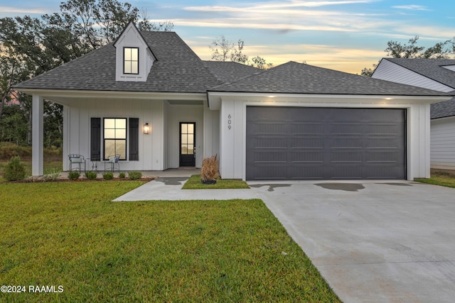 view of front of home with a yard, a porch, and a garage