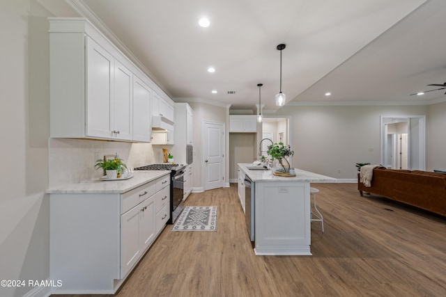 kitchen with decorative light fixtures, white cabinetry, stainless steel appliances, and an island with sink