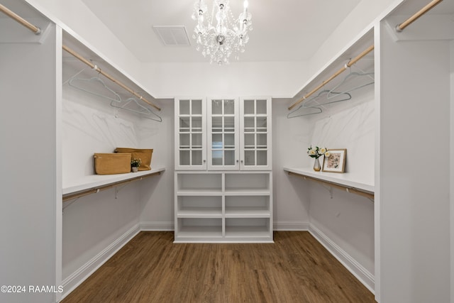 walk in closet with dark hardwood / wood-style floors and a chandelier