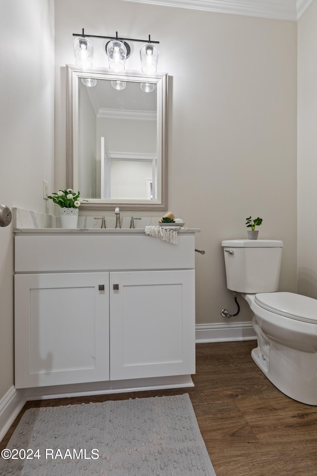 bathroom with toilet, vanity, crown molding, and hardwood / wood-style flooring