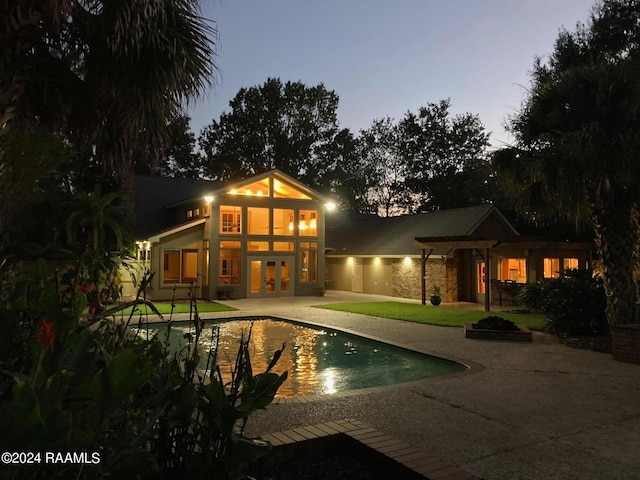 back house at dusk with french doors and a patio