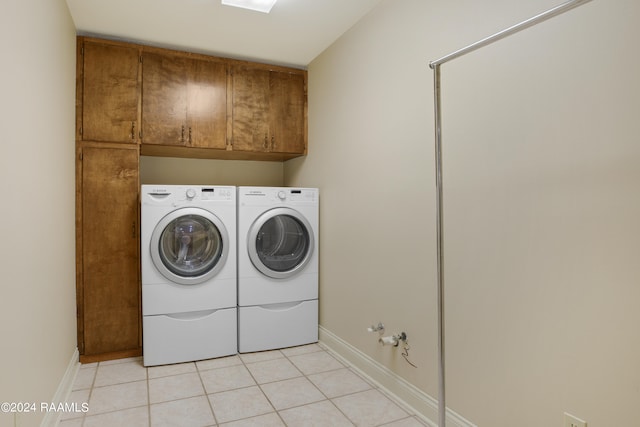 laundry room with cabinets, washing machine and dryer, and light tile floors