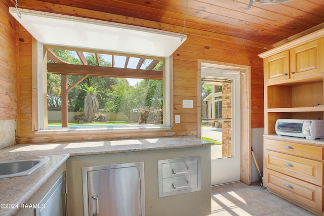 kitchen with light brown cabinetry, wood walls, a healthy amount of sunlight, and light stone countertops