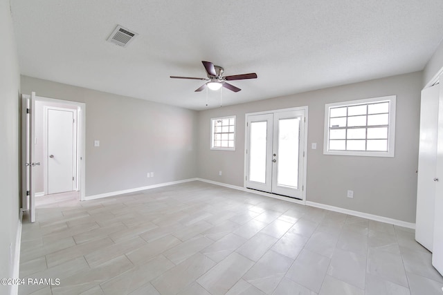 tiled empty room with ceiling fan, a textured ceiling, and french doors