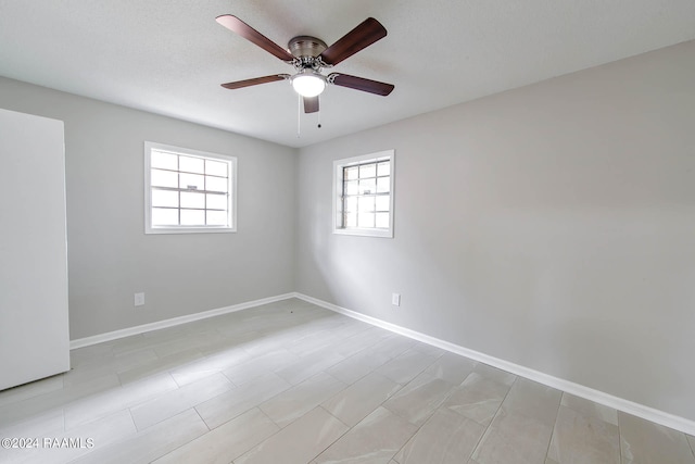 tiled empty room featuring plenty of natural light and ceiling fan