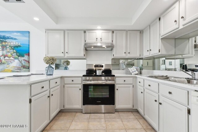 kitchen featuring under cabinet range hood, a sink, white cabinetry, light countertops, and stainless steel electric stove