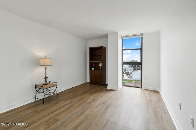 unfurnished room with baseboards, floor to ceiling windows, and wood finished floors