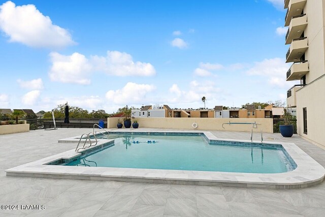 community pool with a patio area and fence