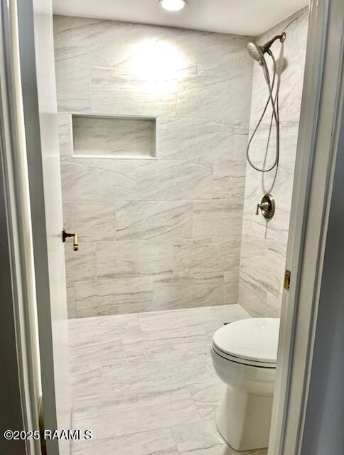 full bathroom with tiled shower and toilet