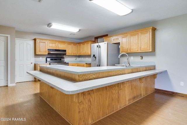 kitchen with a breakfast bar area, stainless steel appliances, and light hardwood / wood-style flooring