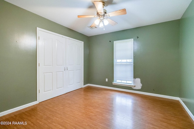 unfurnished bedroom featuring ceiling fan, light hardwood / wood-style floors, and a closet