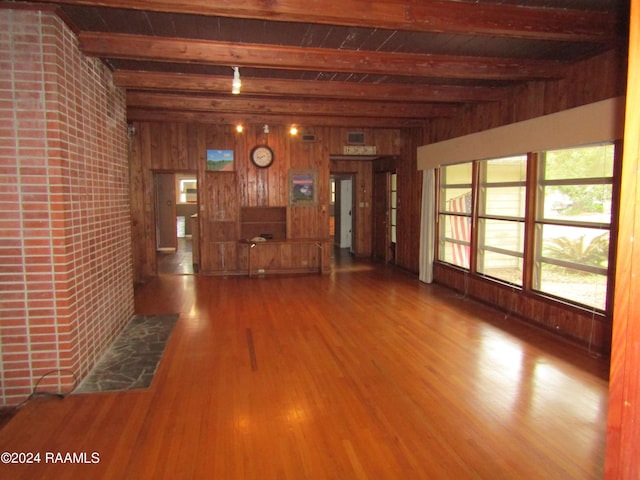 unfurnished living room featuring wood walls, hardwood / wood-style floors, and beam ceiling