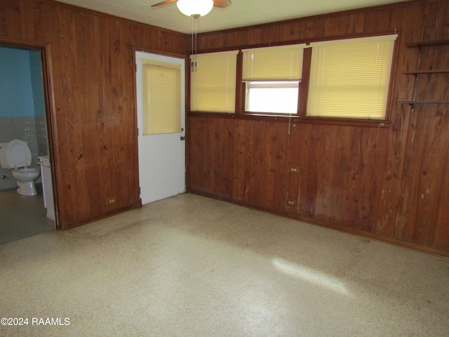 unfurnished bedroom featuring ensuite bathroom and wood walls