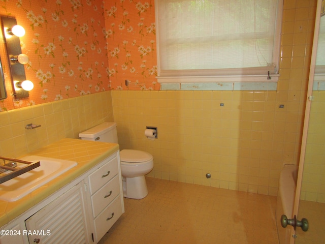 bathroom with tile floors, tile walls, backsplash, vanity, and toilet