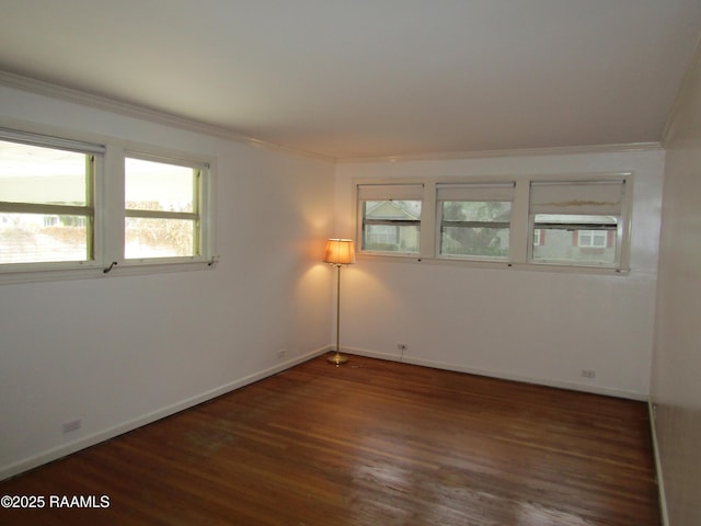 empty room with dark wood-style floors, crown molding, and baseboards