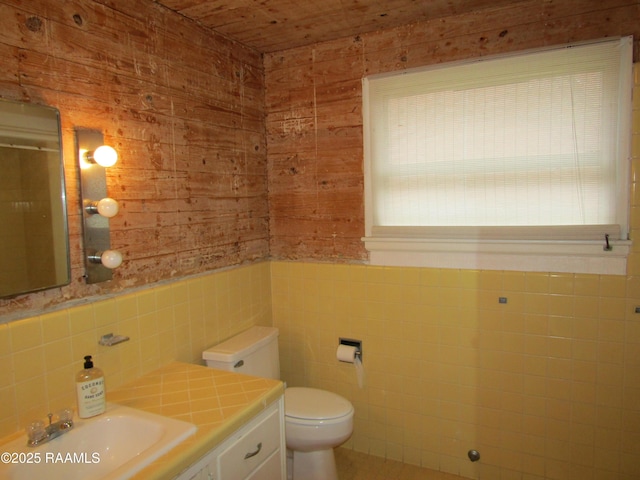 bathroom with tile walls, vanity, and toilet