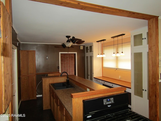 kitchen featuring brown cabinets, dark countertops, a ceiling fan, gas stove, and a sink